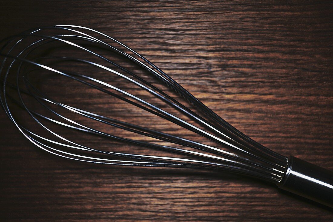 Whisk on wooden background