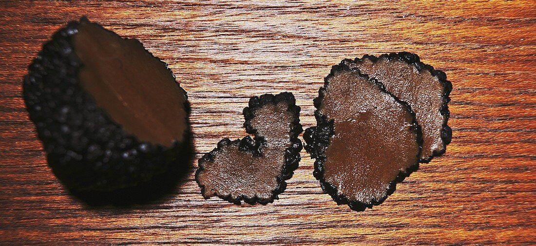 Truffle and truffle slices on wooden background