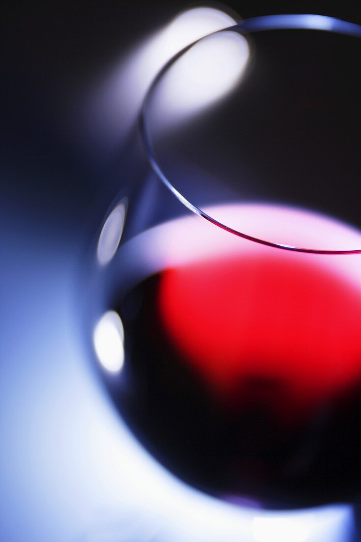 Ein Glas Rotwein vor blauem Hintergrund, Nahaufnahme