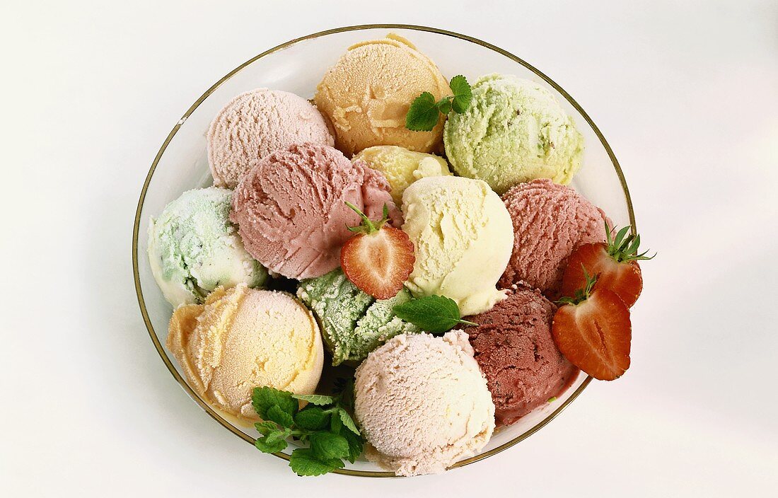 Bowl of different ice creams, strawberries and mint leaves