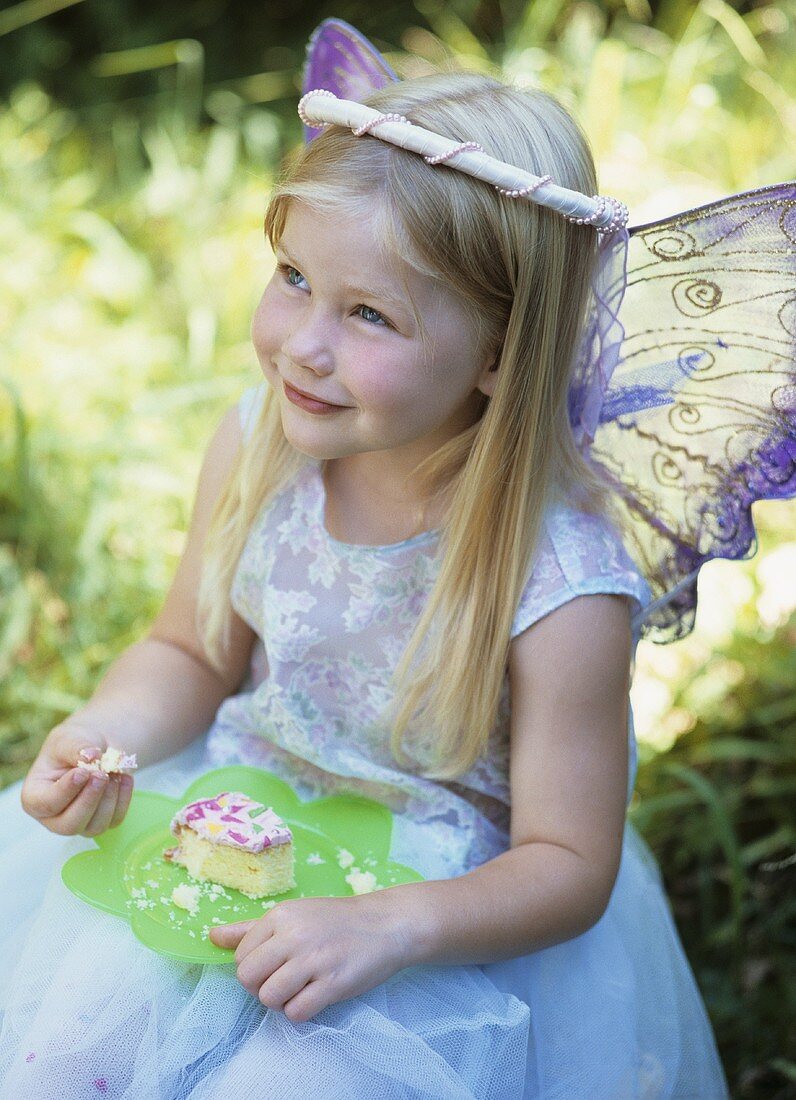 Small fairy eating a piece of birthday cake