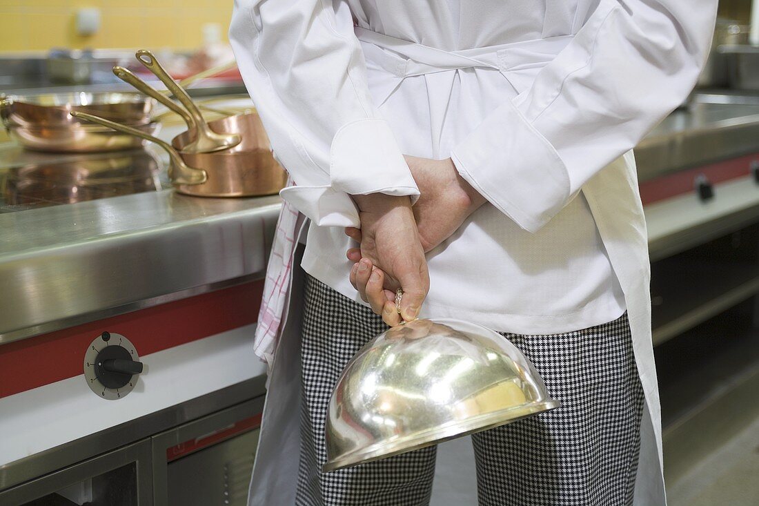 Chef with a domed food cover in his hand