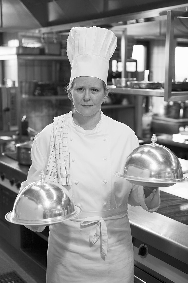 Female chef with two domed serving plates