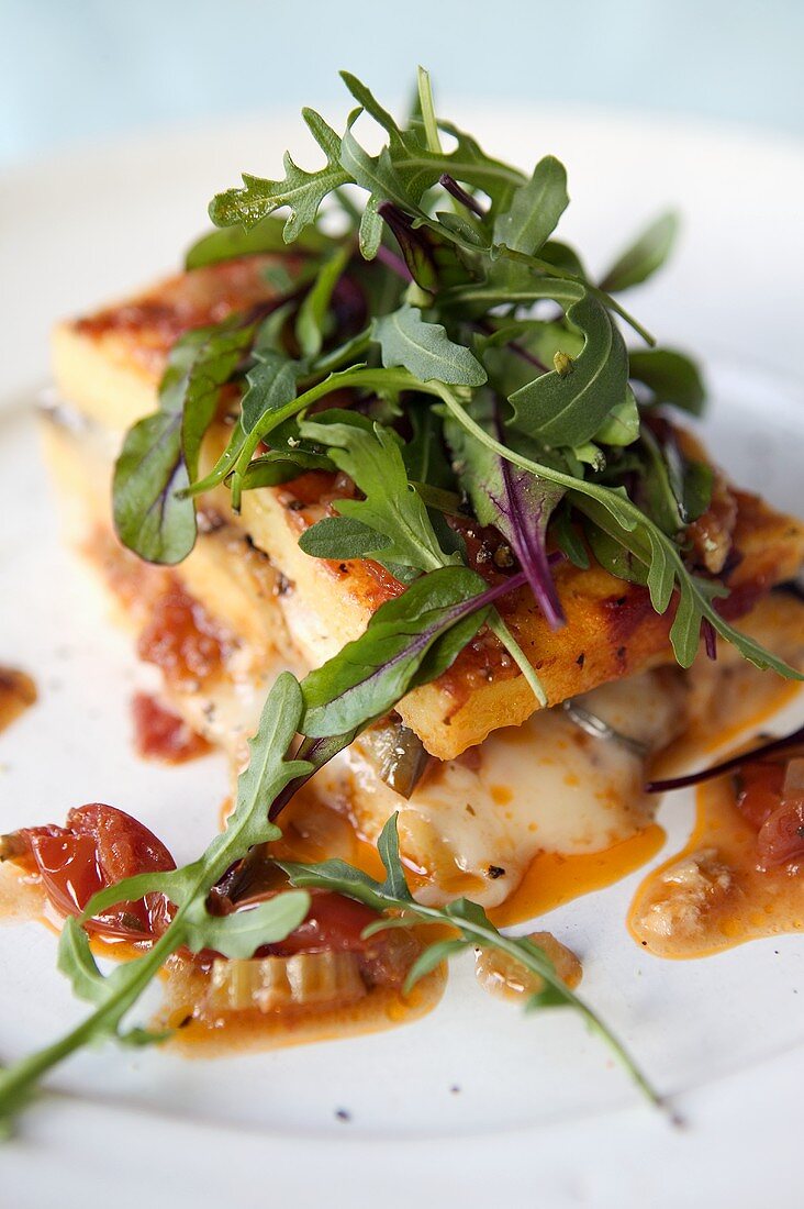 Baked polenta with tomatoes and cheese and rocket