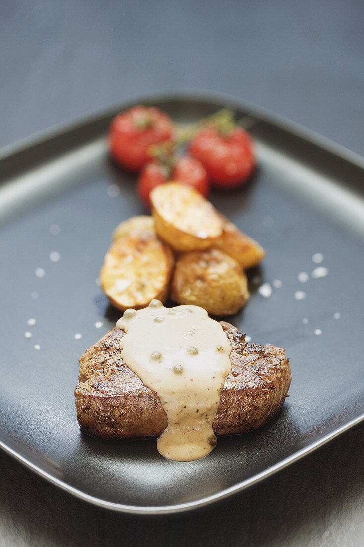 Peppered steak with baked potatoes and tomatoes