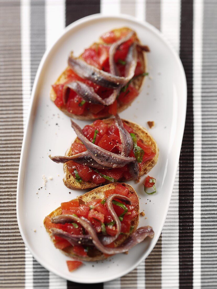 Drei Bruschetta mit Tomaten und Anchovis