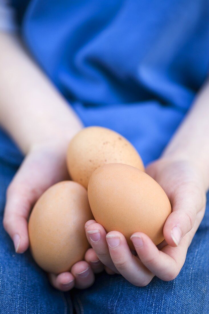 Three eggs lying in someone's hands on their lap