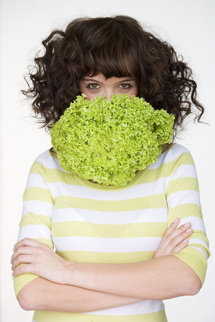 Frau mit Kopfsalat vor dem Mund