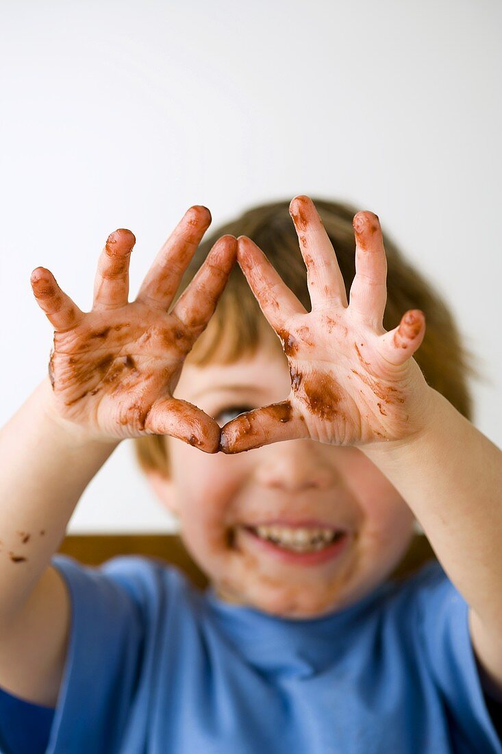 Kleiner Junge mit Schokoladen-Händen