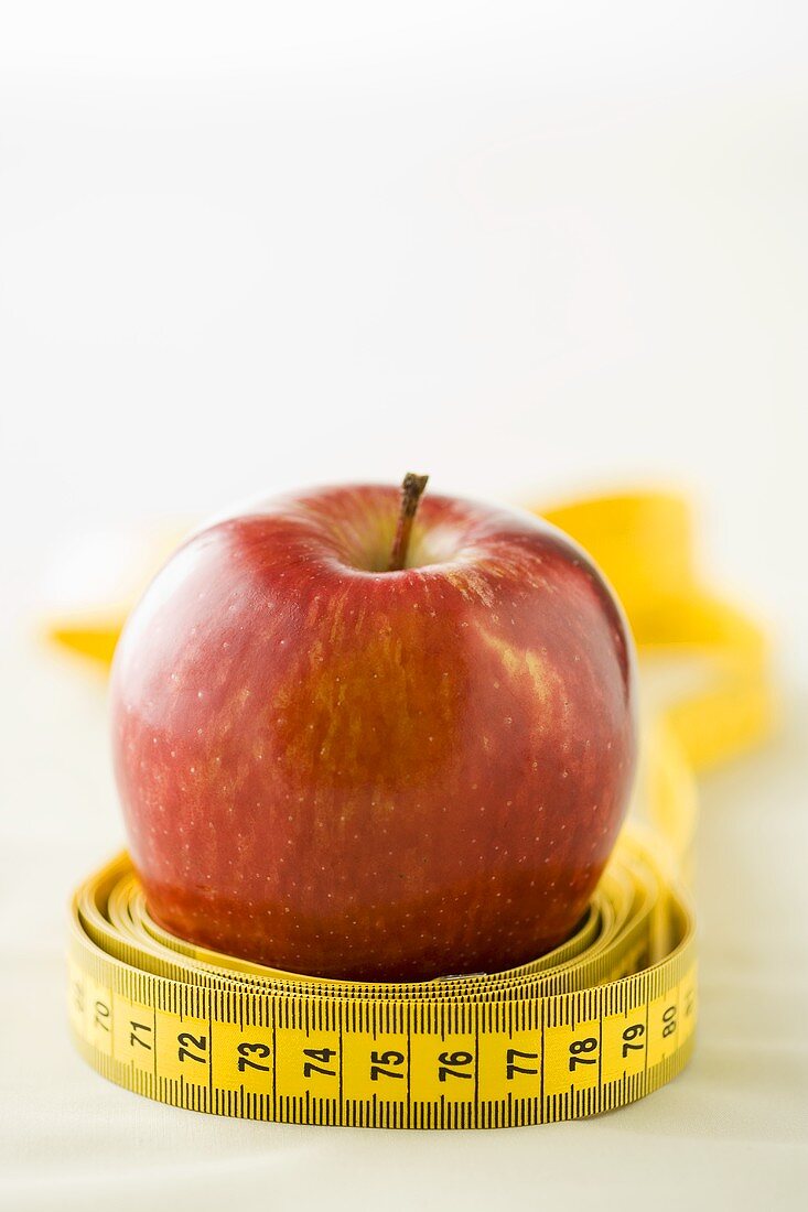 Ein Massband liegt um einen Apfel