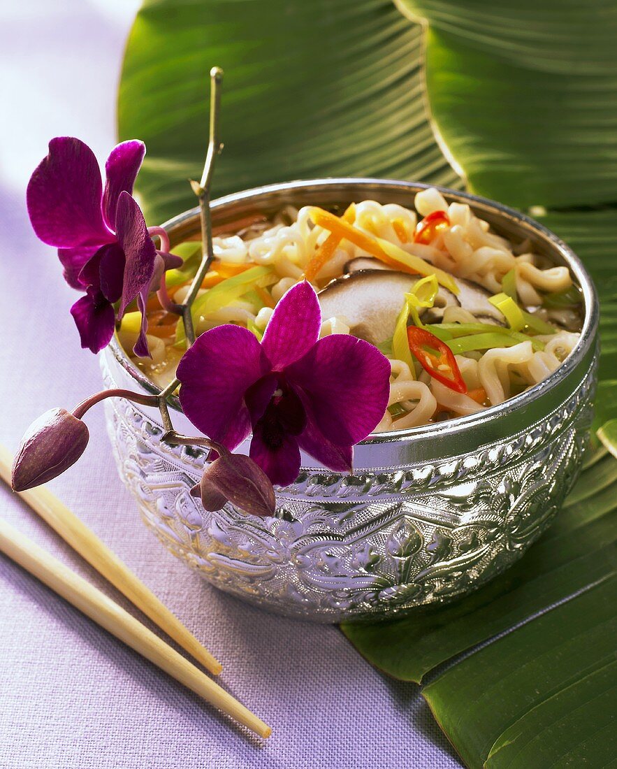 Asian noodle soup with orchids