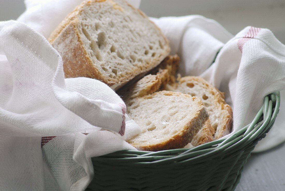 A bread basket with bread, partly sliced
