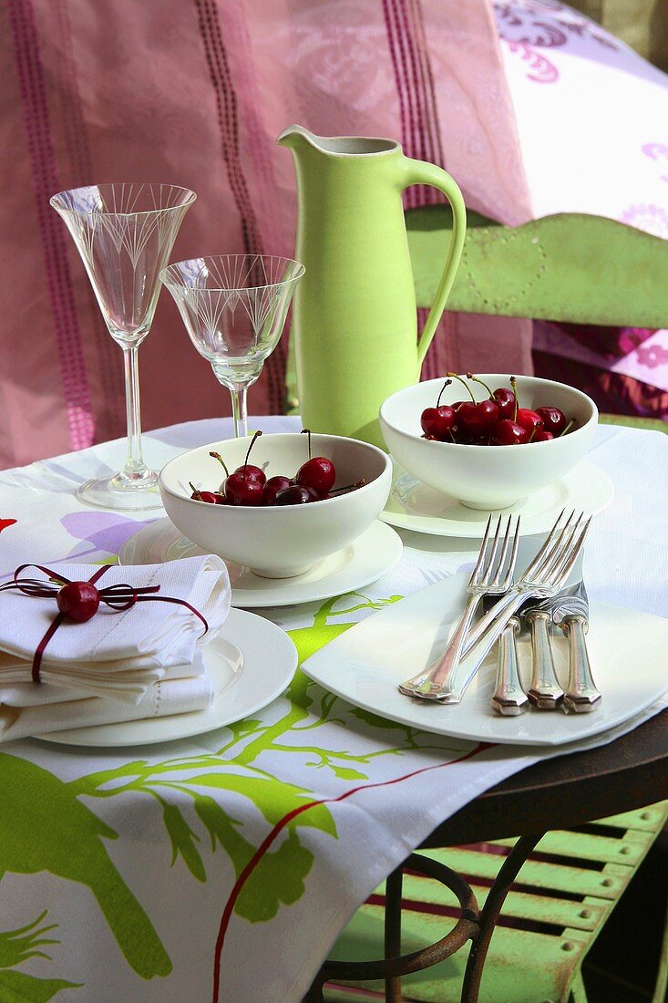 Two small bowls of fresh cherries on laid table