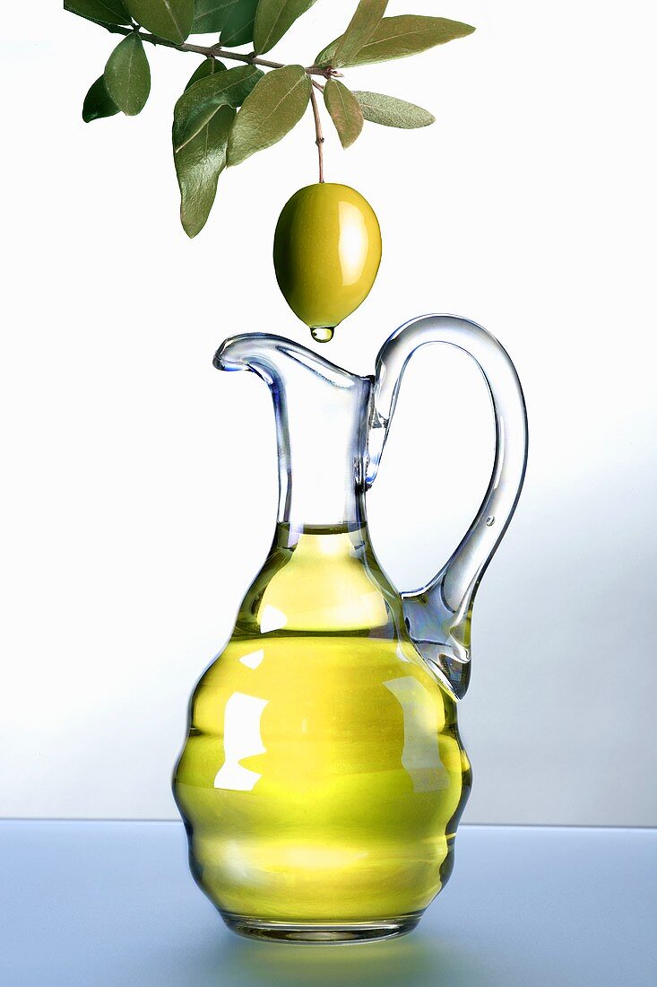 Olivenöl tropft von Olive in Karaffe