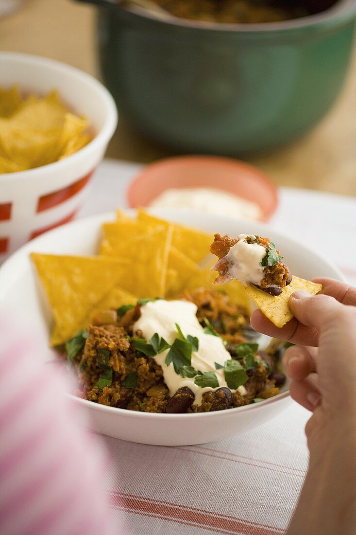 Chili con carne with sour cream and corn chips