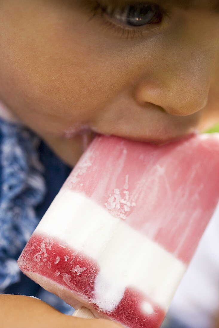 Small girl eating a raspberry ice cream lolly