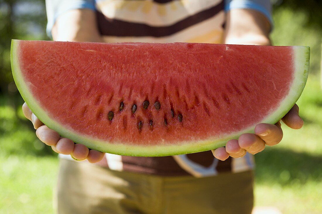 Model holding a slice of watermelon