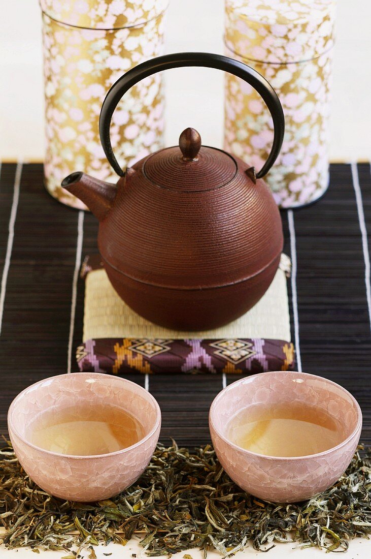Teekanne aus Gusseisen mit zwei Teeschalen und Teedosen