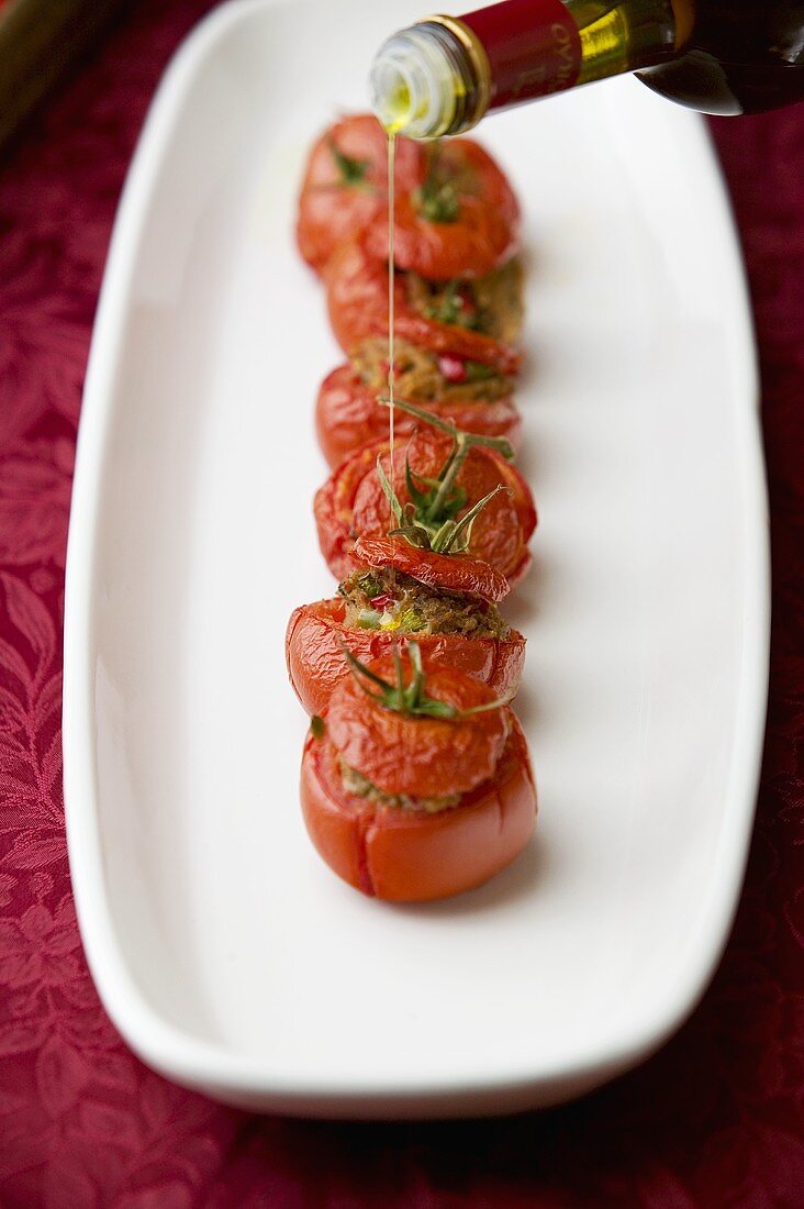 Drizzling olive oil over stuffed tomatoes