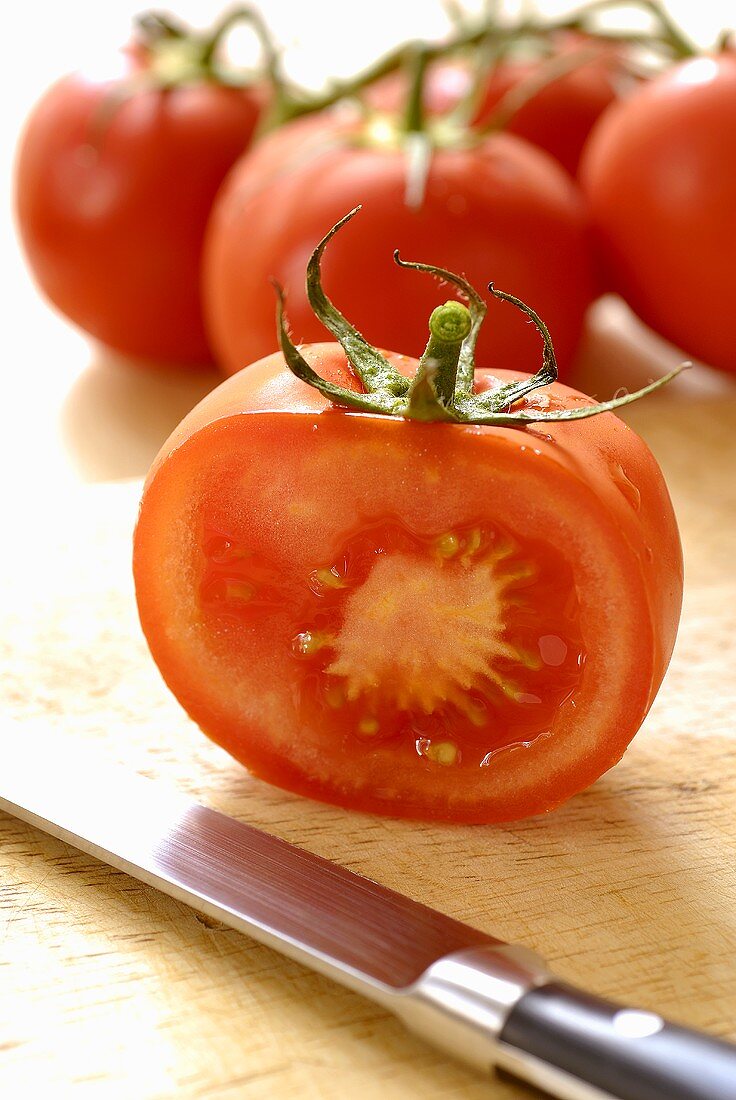 Half and whole tomatoes with knife