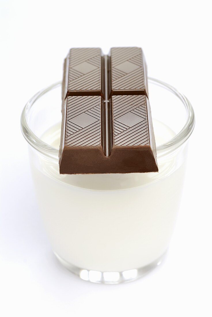 A piece of chocolate on a glass of milk