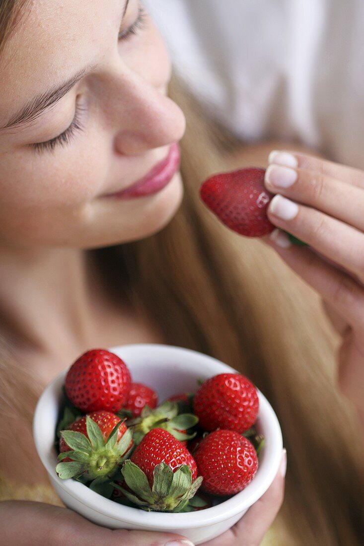 A young woman eating fresh strawberries