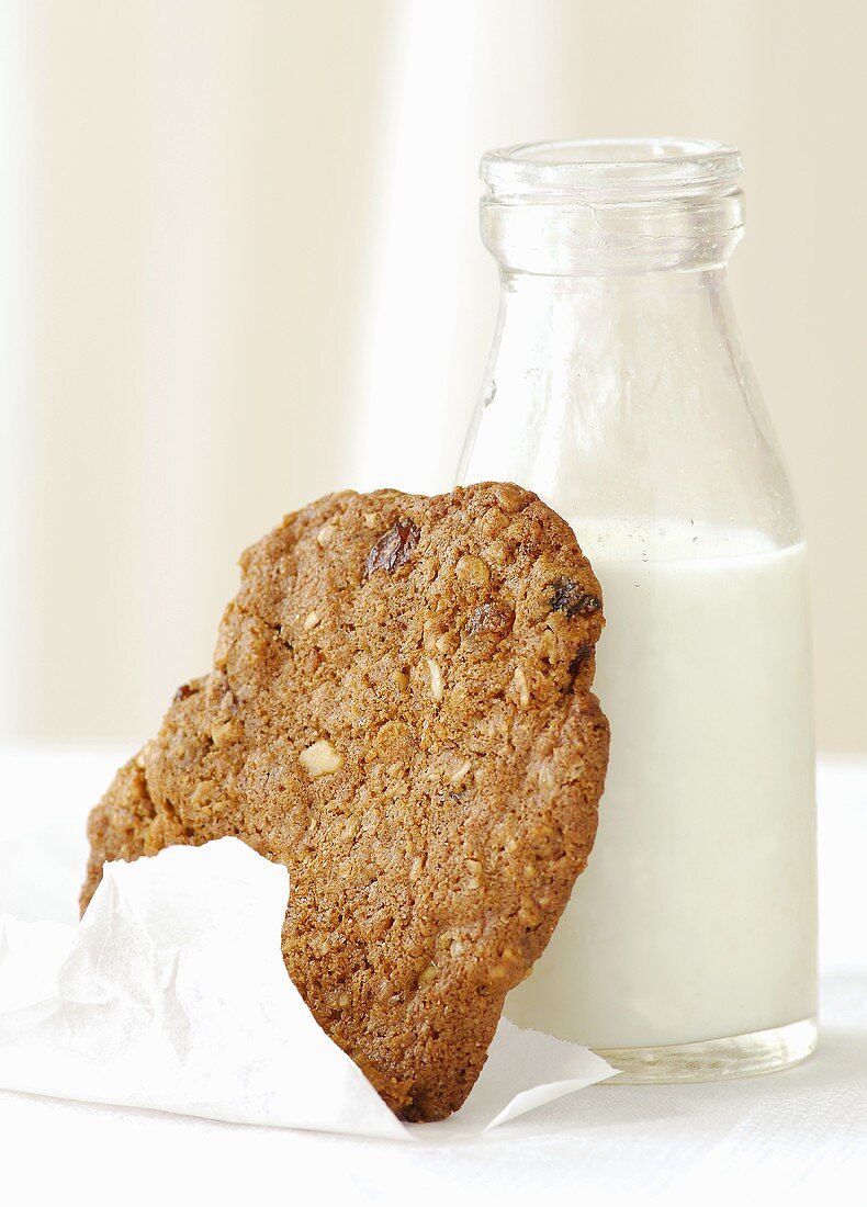 Raisin cookie leaning against a bottle of milk