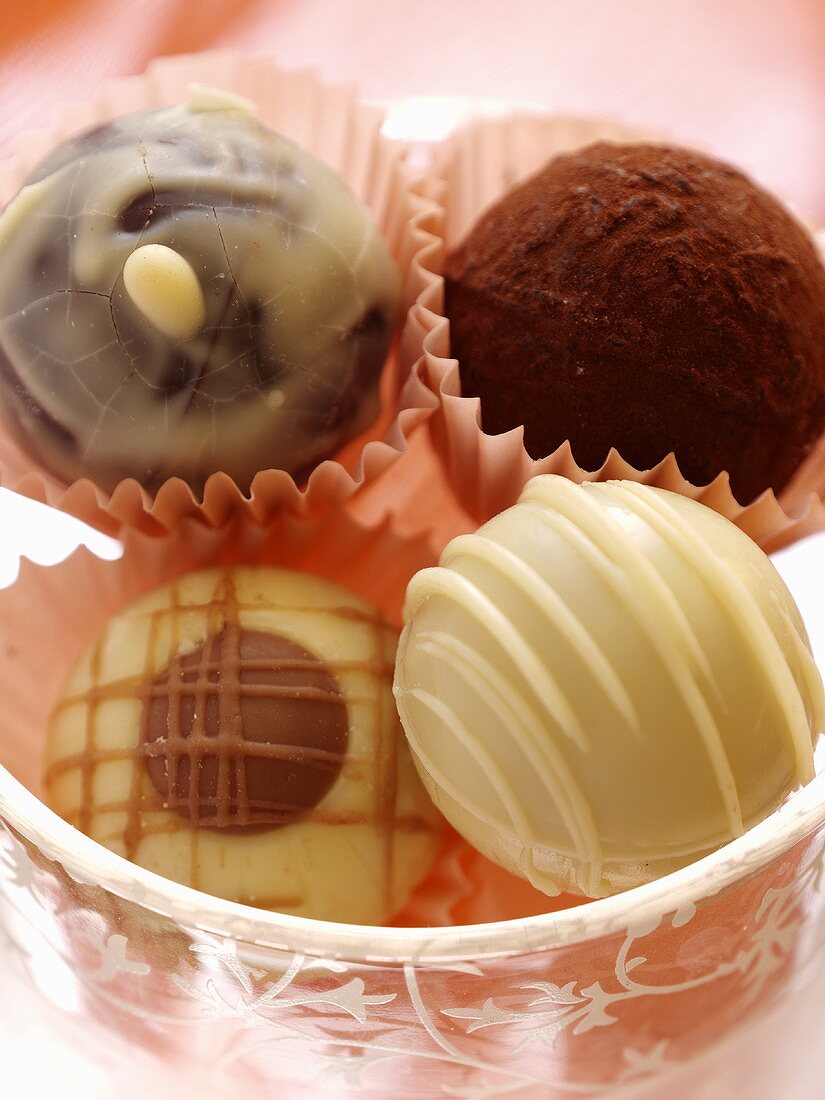 Four chocolate truffles in a glass dish