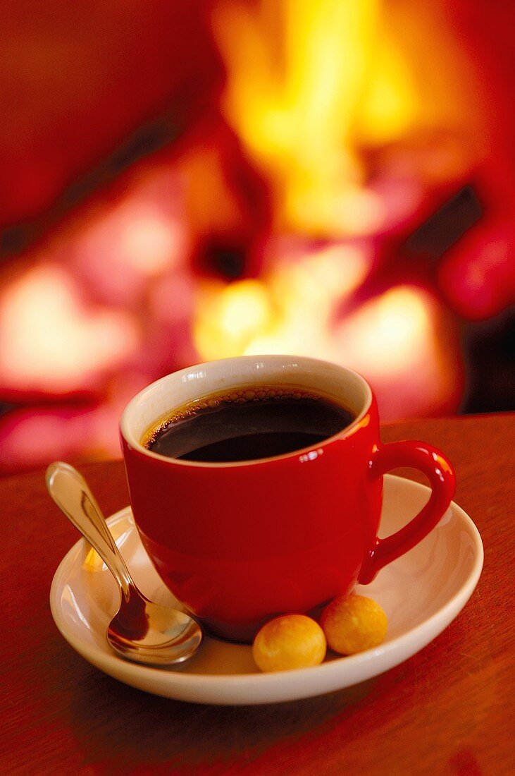 Eine Tasse Kaffee vor einem Kamin-Feuer