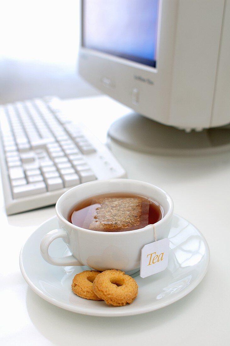 Eine Tasse Tee mit Gebäck am Schreibtisch