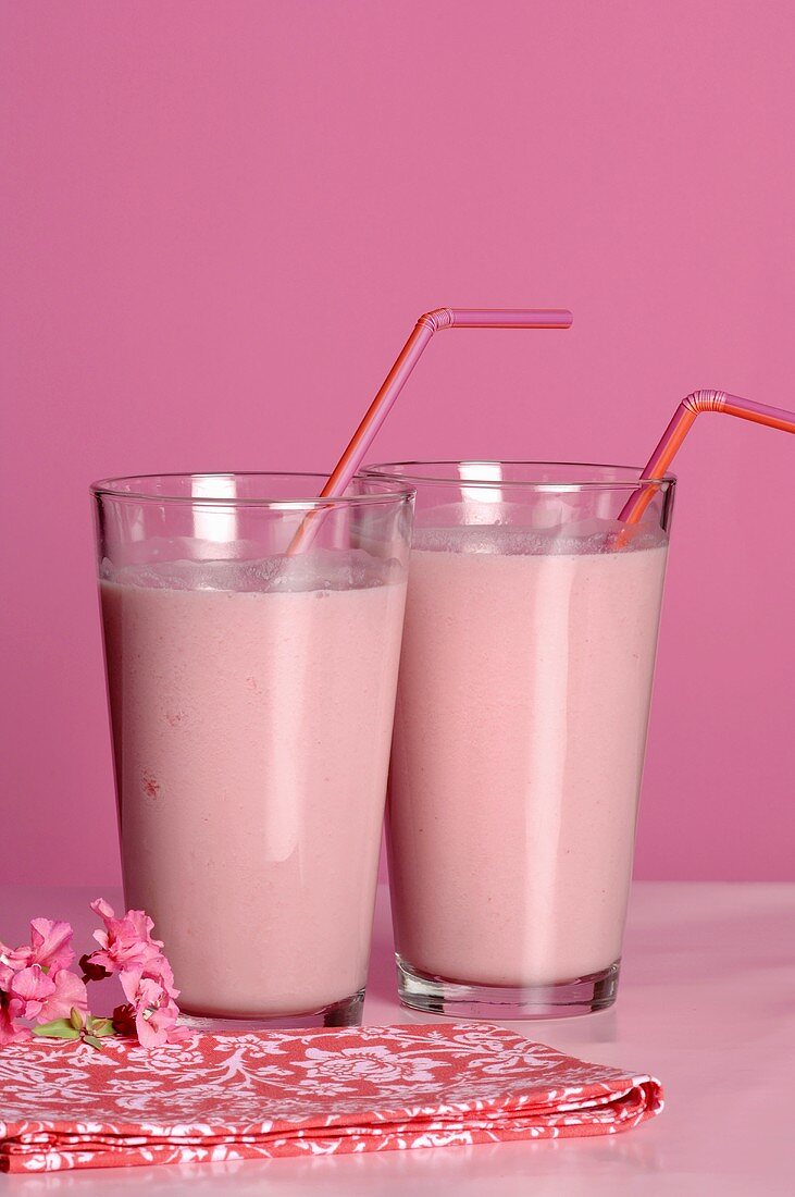 Two glasses of strawberry milk with straws