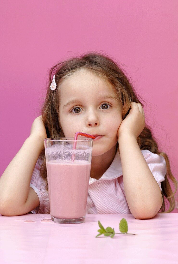 Small girl drinking strawberry milk through a straw