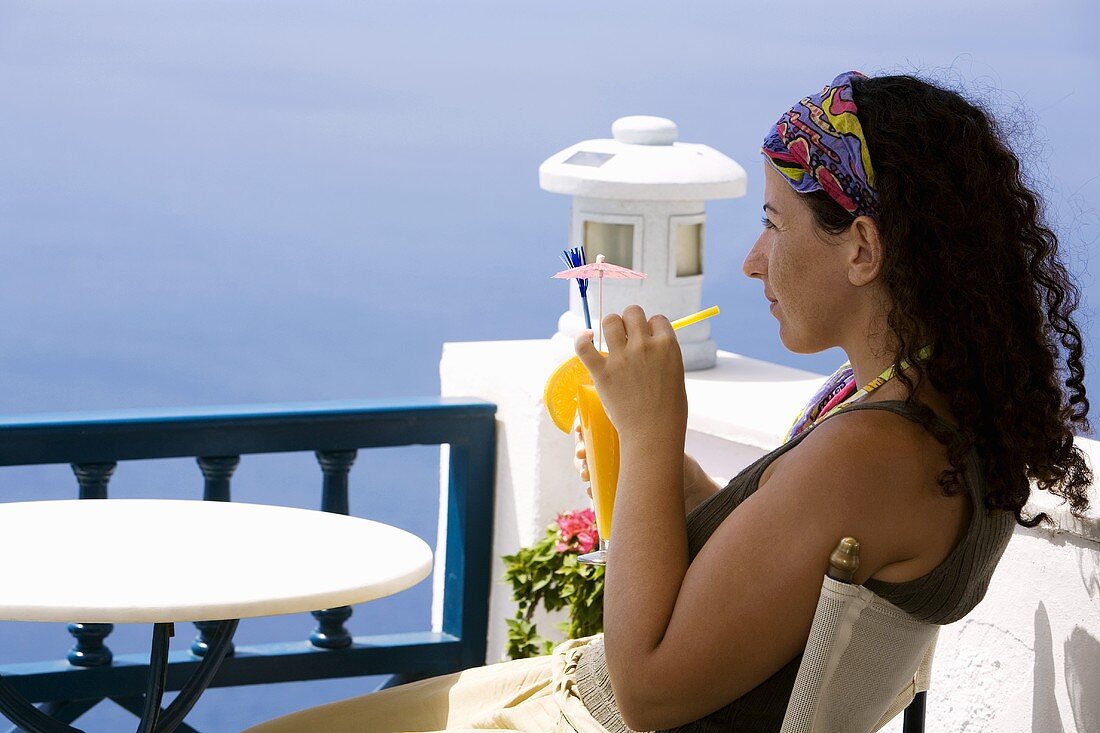 Frau trinkt Orangensaft auf einem Balkon