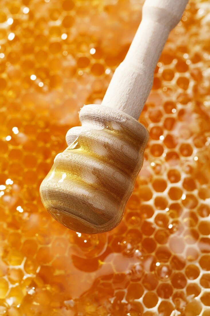 Ein Honiglöffel über einer Honigwabe
