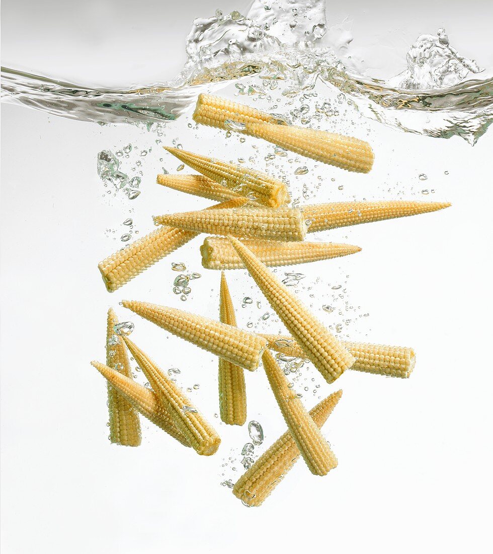 Baby corn cobs falling into water