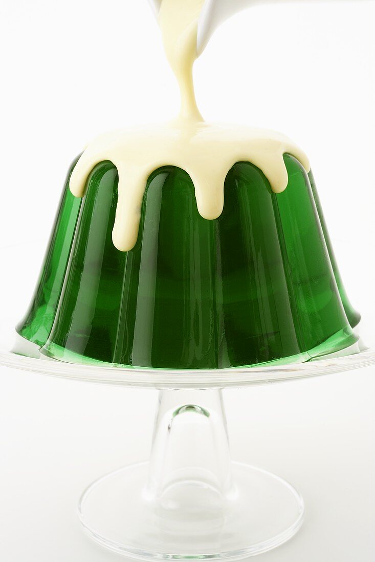 Vanillesauce über Waldmeister-Wackelpudding gießen