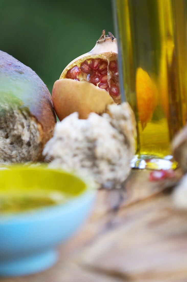 Granatapfel zwischen Brot und Ölflasche