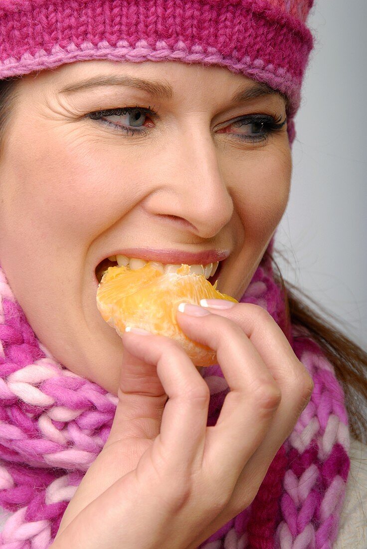 Frau isst einen Orangenschnitz