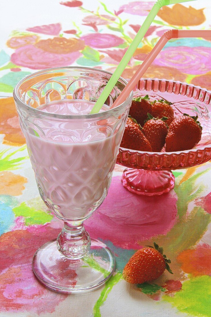 Strawberry shake and strawberries in a glass pedestal bowl