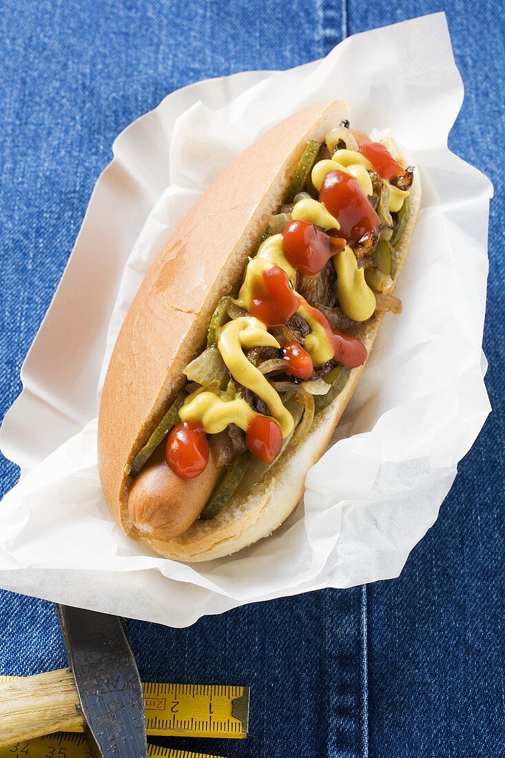 Hot Dog mit Ketchup, Senf und Zwiebeln auf Pappteller