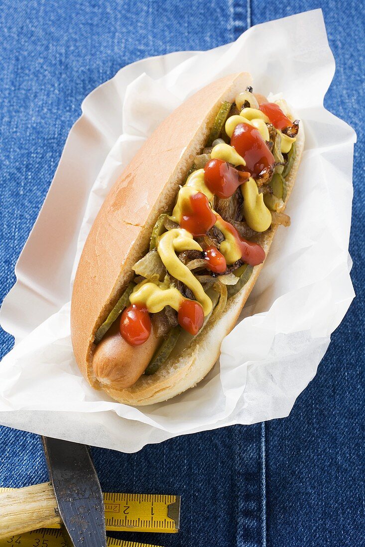 Hot dog with ketchup, mustard and onions in paper dish