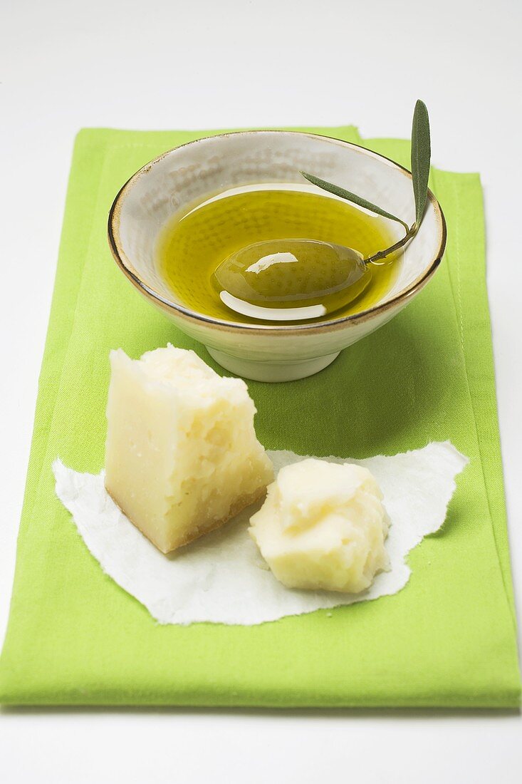Olivenöl im Schälchen mit grüner Olive, Parmesan