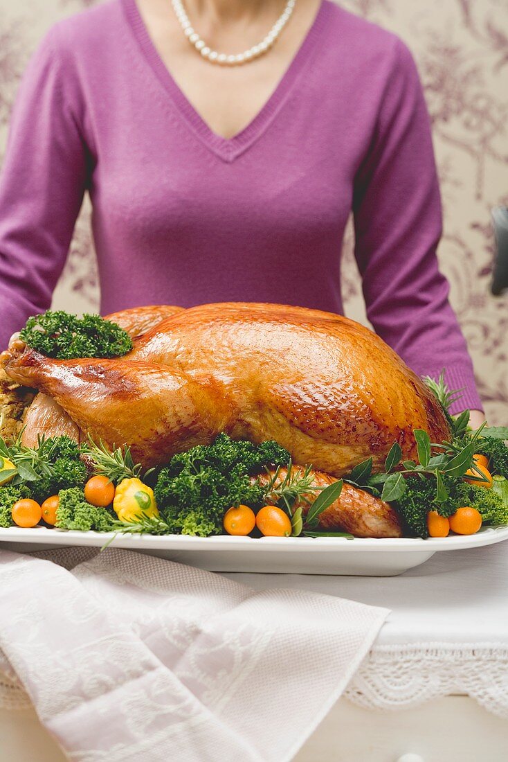 Woman holding a stuffed roast turkey on a platter