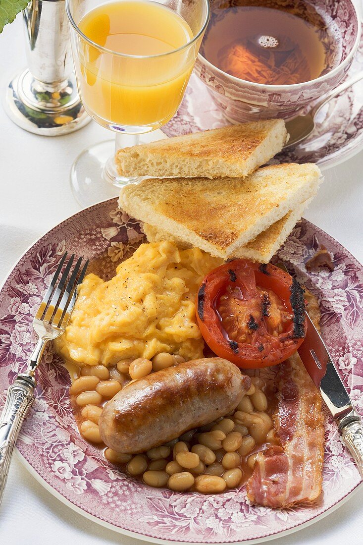 Breakfast with sausage, bacon, beans, scrambled egg, toast & tea (UK)