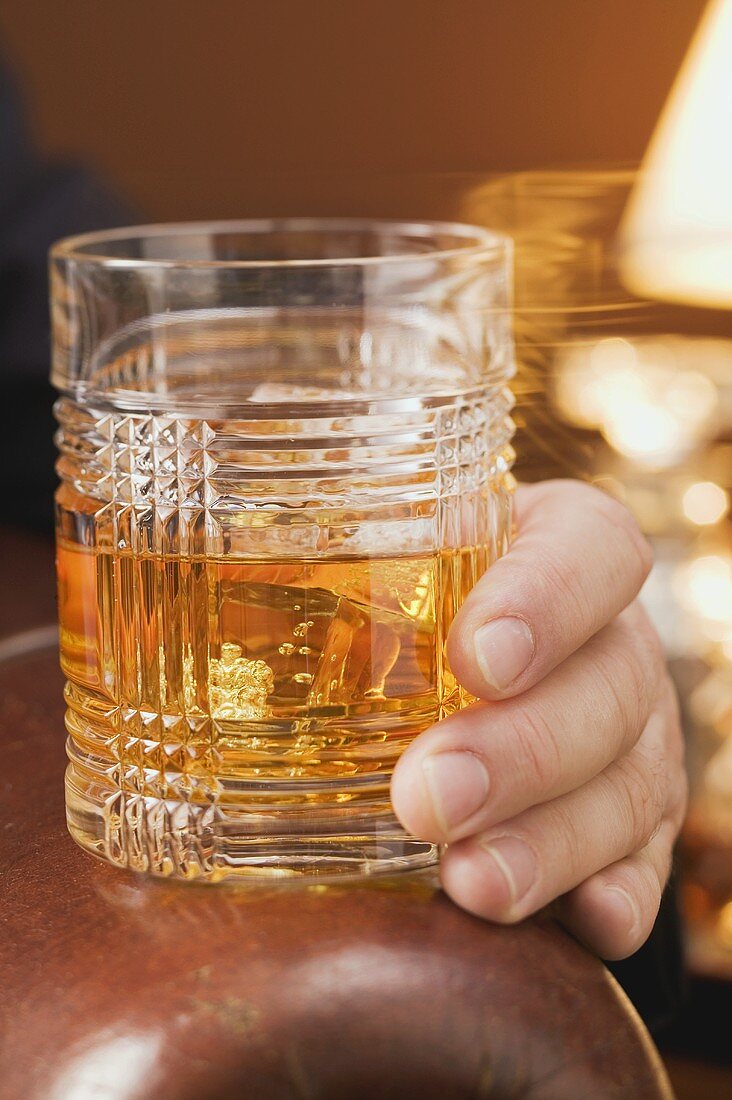 Mann hält Glas Whiskey