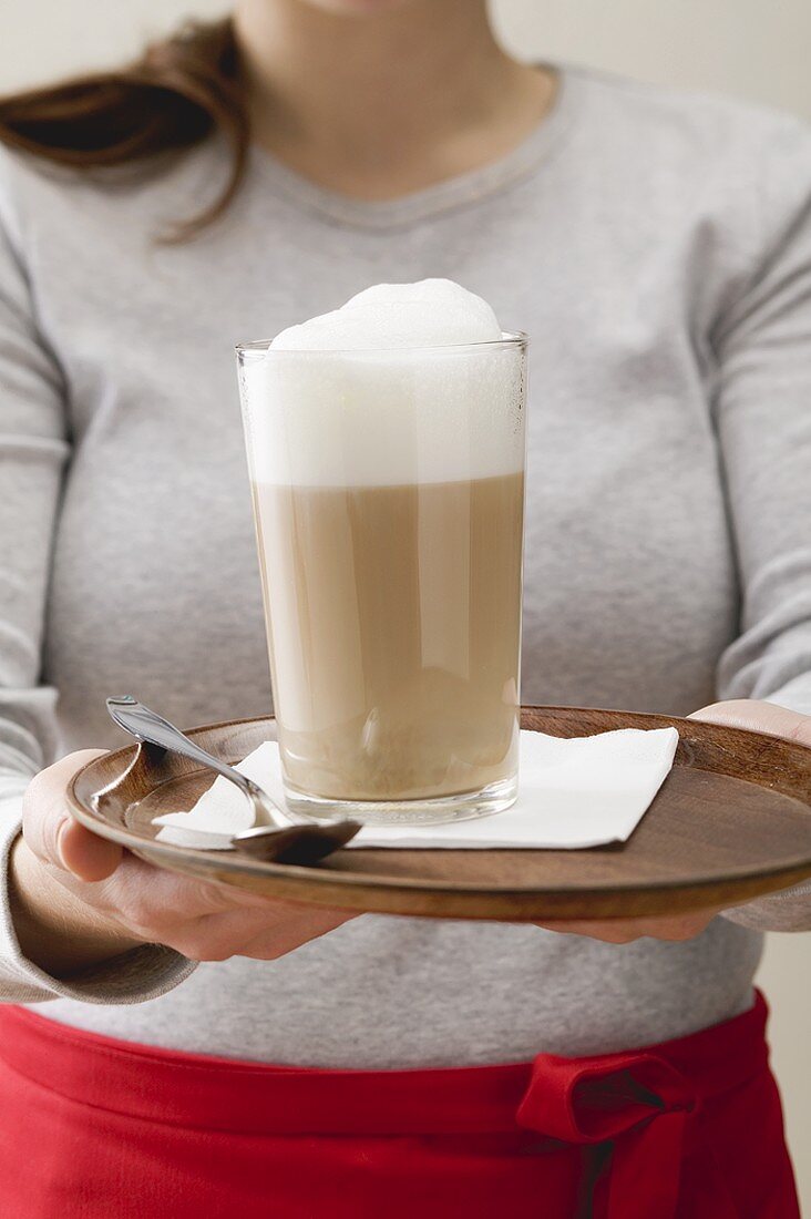 Frau serviert Caffe Latte auf Tablett