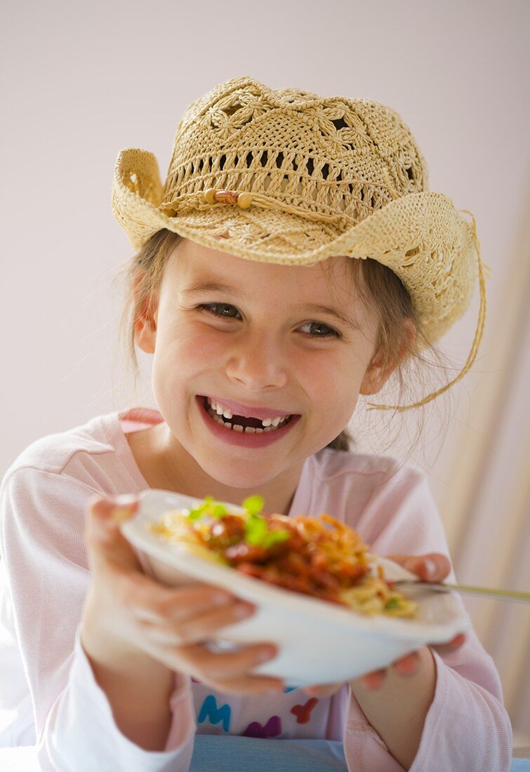 Laughing girl holding plate of spaghetti bolognese