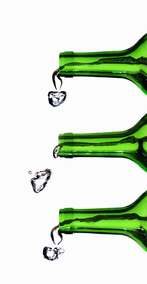 Wasser spritzt aus grünen Flaschen