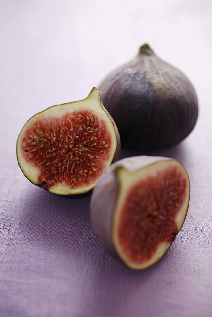 Figs, whole and halved, on mauve background
