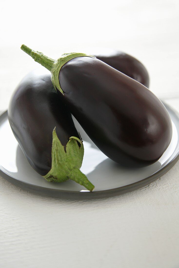 Three aubergines on white plate